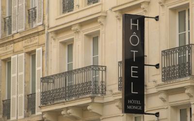 A close-up view of a cream-colored building facade in Paris featuring wrought-iron balconies and a vertical black sign reading "HÔTEL MONGE".