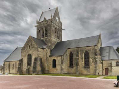 A large stone Gothic church with a prominent tower set under a cloudy sky.
