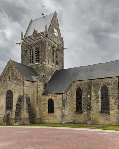 A large stone Gothic church with a prominent tower set under a cloudy sky.