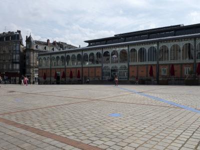 The Limoges Covered Market shows its arched brick and iron facade bordering a paved plaza.