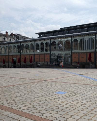 The Limoges Covered Market shows its arched brick and iron facade bordering a paved plaza.