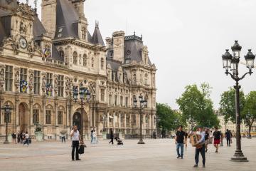 1. The image shows the Conciergerie, a historic palace and former prison in Paris, France, with people walking in the courtyard.