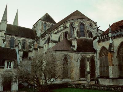 1. The image shows the exterior of a large Gothic-style stone church or cathedral featuring two prominent spires, flying buttresses, and an apse with stained glass windows.