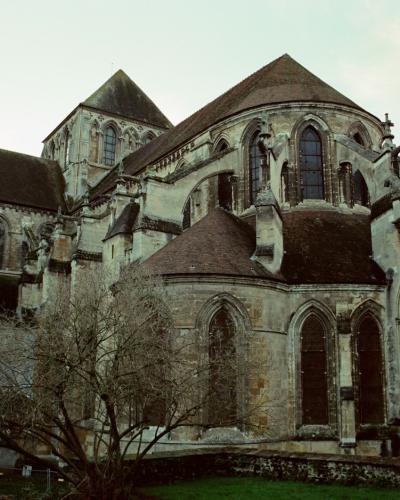 1. The image shows the exterior of a large Gothic-style stone church or cathedral featuring two prominent spires, flying buttresses, and an apse with stained glass windows.