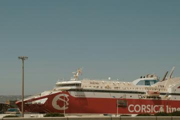 A large red and white ferry ship docked at a port, featuring the "CORSICA line" logo and name on its hull.