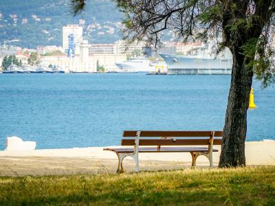 Park bench facing the blue sea at the Jardin de la Plage in Cannes, France.