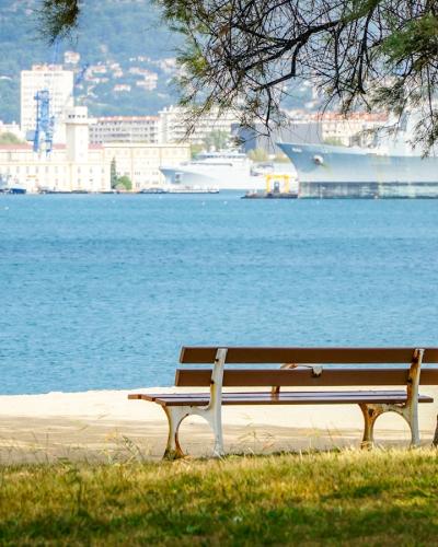 Park bench facing the blue sea at the Jardin de la Plage in Cannes, France.