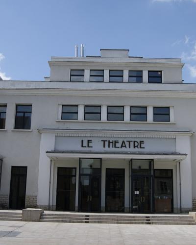 White Art Deco theater building with "LE THEATRE" entrance sign under a blue sky.