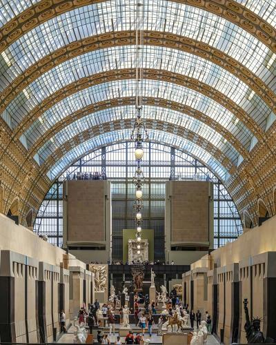 View of the grand central hall with a vaulted glass ceiling and sculptures at the Musée d'Orsay.