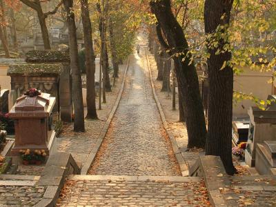 A cobbled, tree-lined avenue between the tombs of Père Lachaise cemetery in autumn