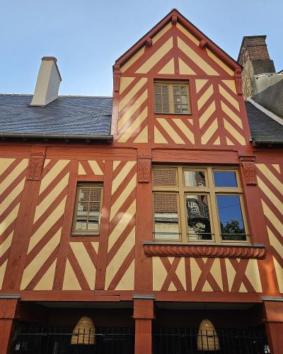 Photographic facade of a red and cream half-timbered Renaissance house in Rennes, France.