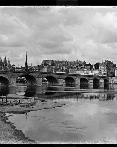 A black and white photograph showing a multi-arched stone bridge spanning a wide river, with a city skyline featuring a large castle on a hill and a cathedral in the background; handwritten text on the left border reads "LOIR ET CHER. A 72 255 X".