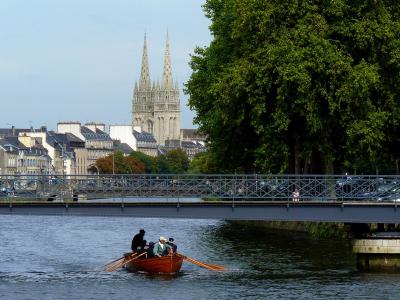 The twin spires of Quimper's Saint-Corentin Cathedral rising above the old town and a footbridge over the Odet river.
