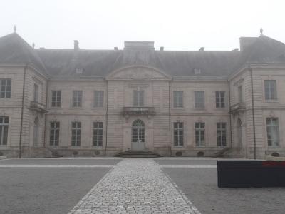 The Palais de l'Évêché in Limoges with a cobblestone path leading to the main entrance on a foggy day.