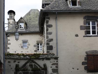 The image shows a close-up view of traditional stone and stucco buildings with slate roofs, characteristic of historic architecture in the Auvergne region of France, specifically within the village of Salers.