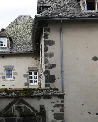 The image shows a close-up view of traditional stone and stucco buildings with slate roofs, characteristic of historic architecture in the Auvergne region of France, specifically within the village of Salers.