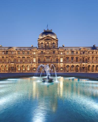 Cour Carrée of the Louvre Museum at dusk with a glowing central fountain.