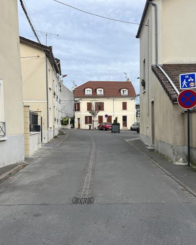 A paved residential street in a French town, featuring a blue street sign on the right wall that reads "RUE DE LA HALLE", along with traffic signage and surrounding buildings.
