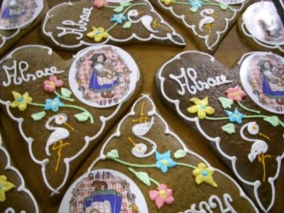A close-up view of several decorated gingerbread cookies (pain d'épices) featuring white icing designs, colorful sugar flowers, and circular edible paper inserts depicting figures in traditional Alsatian dress with text like "Alsace" and "SAIT".