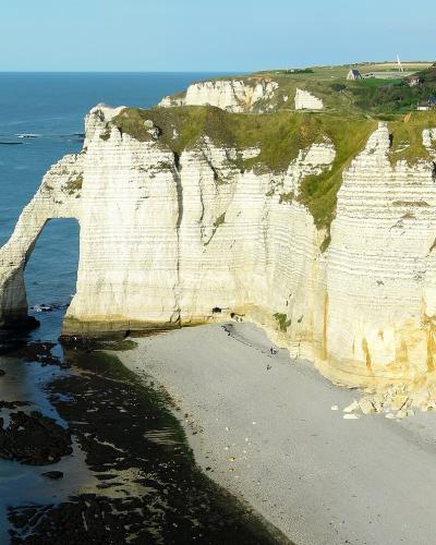 The image shows the famous white chalk cliffs of Étretat in Normandy, France, featuring the natural arch known as "Porte d'Aval" and the sea stack known as "L'Aiguille" (Needle).