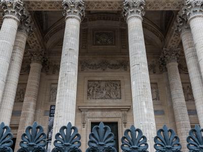 A close-up of the pediment and entablature of a neoclassical building, featuring sculptural reliefs and the French inscription "AUX HOMMES LA PATRIE RECONNAISSANTE" (To the men the grateful fatherland) in gold lettering above Corinthian columns.