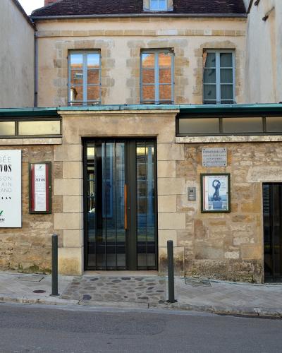 The image shows the exterior entrance of a building with a sign reading "MUSÉE ZERVOS MAISON ROMAIN ROLLAND VÉZELAY" and a vertical banner on the right side also displaying "VÉZELAY".