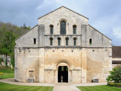 A person stands in the arched doorway of the Abbey Church of Fontenay, a historic Cistercian building in Marmagne, France.