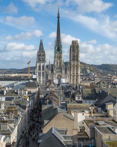 A high-angle view looking down a crowded street lined with historic buildings towards the Rouen Cathedral, with the filename indicating the photo was taken from the Gros Horloge archway.
