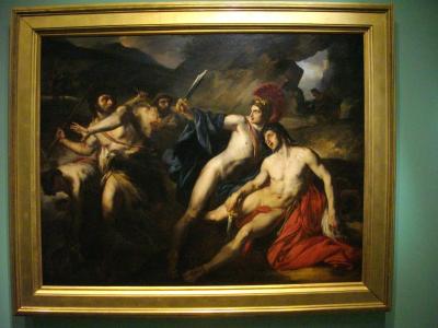 A large, framed Baroque-style painting depicting a dramatic mythological or historical scene with multiple nude and semi-nude figures in dynamic poses, mounted on a teal-colored wall inside what appears to be a museum gallery.