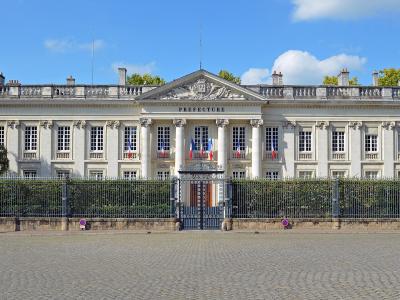 1. A grand neoclassical building with a pediment, columns, and the word "PREFECTURE" inscribed above the entrance, fronted by a wrought-iron fence and cobblestone plaza under a blue sky.