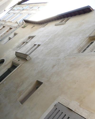A low-angle, tilted photograph of the beige stucco facade of a historic building featuring arched windows and stone window surrounds.