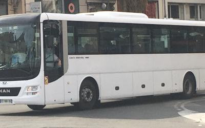 A white MAN Lion's Intercity coach bus driving on a city street, with visible signage including "Ligne 832" on the destination display and a French license plate.
