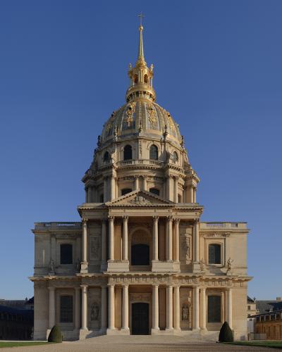 An interior view of a grand stone staircase with ornate black iron railings, tall arched windows, and a vaulted ceiling with faded frescoes, identified by the filename as the "Escaliers Est" (East Stairs) of Les Invalides.