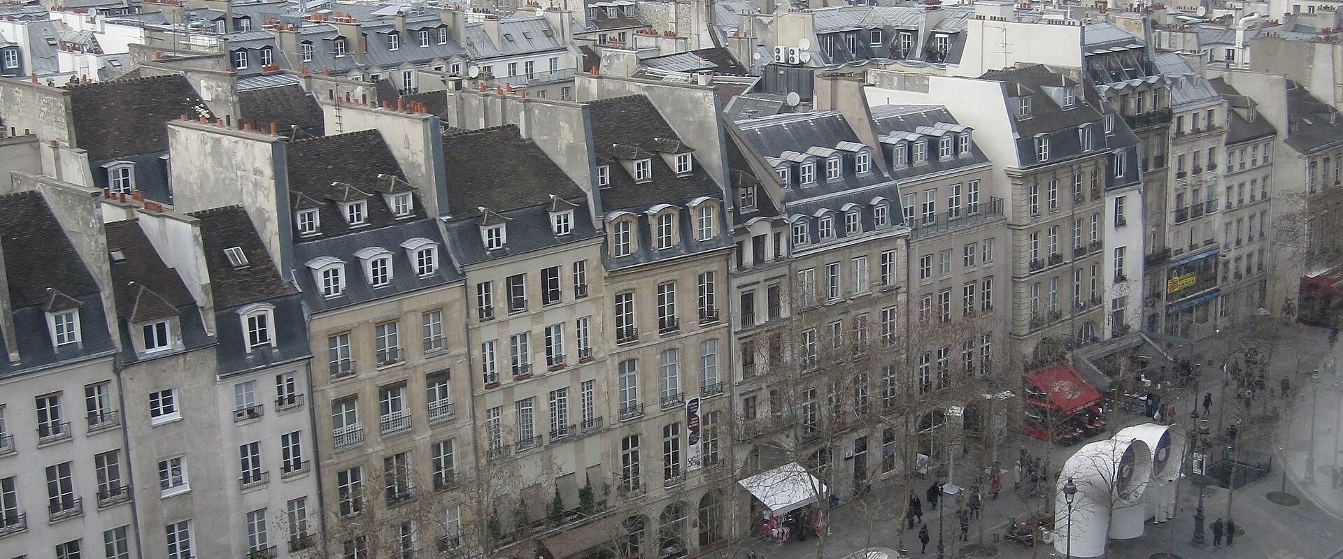 A high-angle view of the Place Georges Pompidou in Paris, showing the distinctive white "air bubble" ventilation structures, surrounding Haussmannian buildings, and the Sacré-Cœur Basilica visible on Montmartre in the distance.
