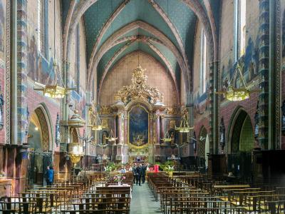 The image shows the interior nave and chancel of a large Gothic church with distinctive blue vaulted ceilings decorated with gold stars, painted murals on the walls, and an ornate golden altarpiece.