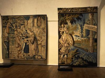 Two large, historic tapestries displayed on a museum wall with wooden flooring and informational plaques beneath them.