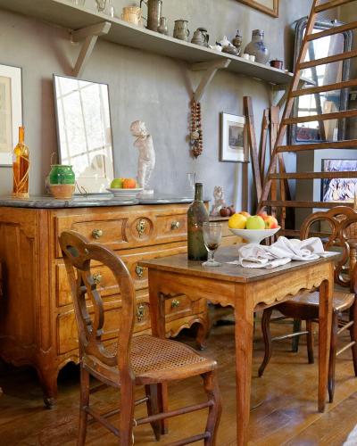 One line: The interior of a historic artist's studio featuring wooden furniture, a ladder, shelves with pottery, and a rope barrier indicating it is a preserved museum space.