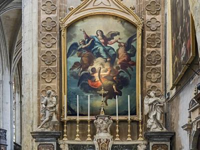 The image shows an ornate Baroque-style altar with a large painting of the Assumption of the Virgin Mary, flanked by two angel statues and set within a stone architectural niche featuring quatrefoil motifs.