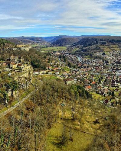 A panoramic landscape view of a town nestled in a river valley with a prominent cluster of historic buildings perched on a rocky cliff overlooking the settlement below.