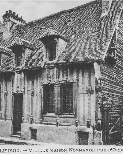 A black and white photograph of a historic half-timbered house with a steep tiled roof and dormer windows, featuring a sign for "CASINO A GAUCHE" on the right side.
