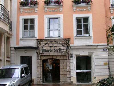 The image shows the entrance to a building with a sign reading "Caveau des Chansons de France" and "Musée du Vin," located at number 5 on a wet street with a silver car parked nearby.