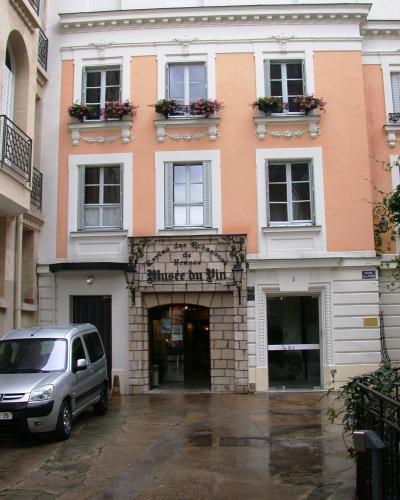 The image shows the entrance to a building with a sign reading "Caveau des Chansons de France" and "Musée du Vin," located at number 5 on a wet street with a silver car parked nearby.