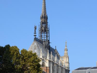 The ornate Gothic spire of Sainte-Chapelle in Paris rises against a blue sky.