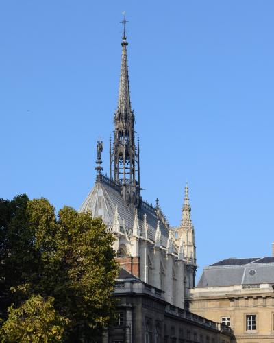 The ornate Gothic spire of Sainte-Chapelle in Paris rises against a blue sky.