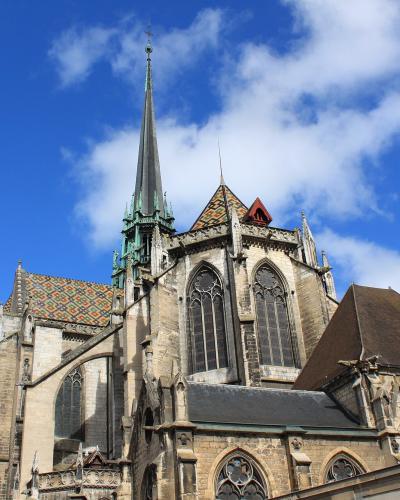 View of the Gothic spire and colorful tiled roofs of the Cathedral of Saint-Bénigne in Dijon.