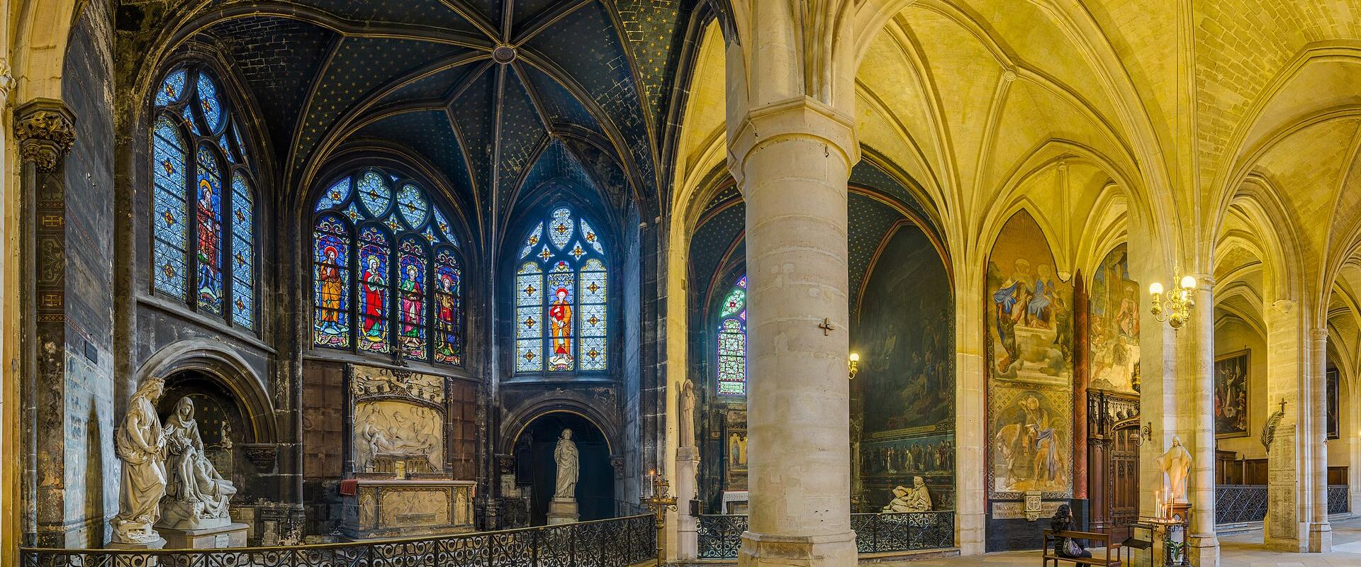 The interior of a Gothic-style church featuring vaulted ceilings, stained glass windows, stone columns, and religious statues and paintings.