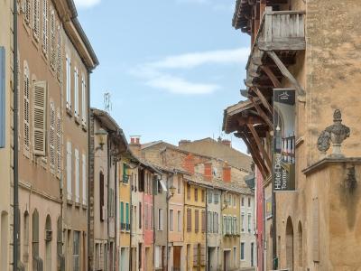A narrow, curving street in a historic French town lined with multi-story buildings featuring shutters and timber framing, with a vertical banner on the right reading "Hôtel-Dieu Tournus".