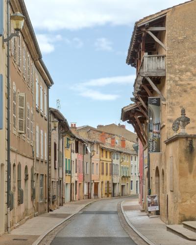A narrow, curving street in a historic French town lined with multi-story buildings featuring shutters and timber framing, with a vertical banner on the right reading "Hôtel-Dieu Tournus".