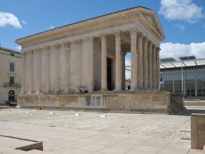 The image shows the ancient Roman temple known as the Maison Carrée in Nîmes, France, with its distinctive Corinthian columns and pediment, and the modern glass-fronted Carré d'Art museum building is visible in the background to the right.