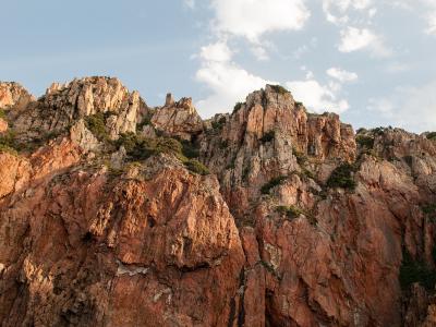 Spiky red granite cliffs and jagged rock spires rise against a blue sky.